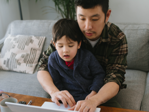 Man and child sitting in front of a laptop
