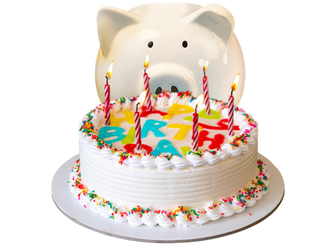 Piggy bank siting behind a birthday cake